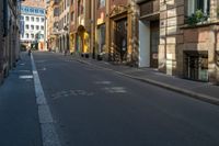 a yellow street light sitting on the side of an empty street in a city surrounded by tall buildings