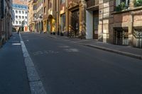 a yellow street light sitting on the side of an empty street in a city surrounded by tall buildings