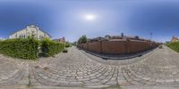 a street with many houses in it that looks like a camera lens and has brick pavement