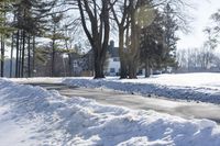 a red fire hydrant sitting in the snow near trees outside a house during wintertime