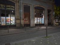 the sidewalk in front of the store is lined with fake flowers on glass windows in the dark