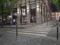 there are a lot of trees in the street outside the shops window at night,