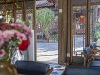 an open patio with a few chairs and flowers on the table and outside doors of the dining area