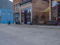 a red fire hydrant sitting in front of an old store window and building next to an open air field