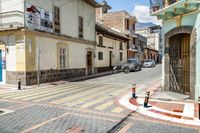 a red yellow and white checkered crosswalk on a street with cars parked next to it