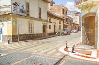 a red yellow and white checkered crosswalk on a street with cars parked next to it