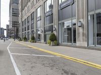 a sidewalk and two fire hydrants line the corner of a street next to tall buildings