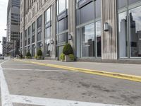 a sidewalk and two fire hydrants line the corner of a street next to tall buildings