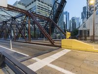 an outdoor bridge with a yellow bench in the middle and high buildings in the background