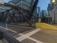 an outdoor bridge with a yellow bench in the middle and high buildings in the background