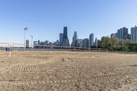 an empty beach with volleyball nets in front of a large city skyline as seen from the sand