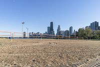 an empty beach with volleyball nets in front of a large city skyline as seen from the sand