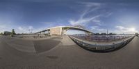 a fish eye lens image of an empty city street and a pedestrian crossing over a bridge