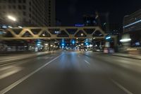 blurred photo at night of city street and highway with roadway lights in motion passing over road