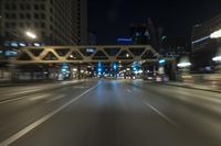 blurred photo at night of city street and highway with roadway lights in motion passing over road