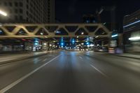 blurred photo at night of city street and highway with roadway lights in motion passing over road