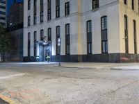 the sidewalk in front of a building at night time shows off street signs and an intersection