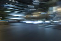 blurred view of a street at night showing cars passing by and skyscrapers in the background