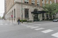 two men walk in front of an apartment building across from a red stop sign on the street