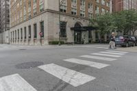 two men walk in front of an apartment building across from a red stop sign on the street