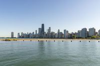 view of city skyline from lakefront with boats on beach and sand in foreground