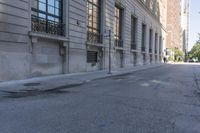 a sidewalk on a city street next to tall buildings with windows on the side of it