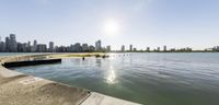 water on a lake next to a large city skyline with high buildings in the background