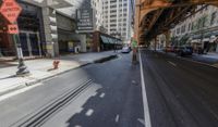 a street in a big city is lined with lots of buildings, including an overpass that overlooks a parking garage