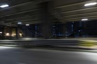 a blurry photo of a highway at night time and buildings in the distance taken by the car