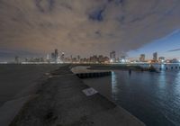 the skyline is lit up for night on the water's edge in the city