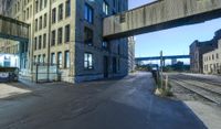 a long train track next to a tall building with windows and a bridge above it