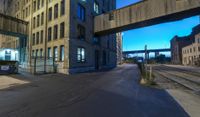 a long train track next to a tall building with windows and a bridge above it