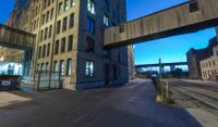 a long train track next to a tall building with windows and a bridge above it