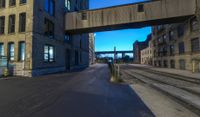 a long train track next to a tall building with windows and a bridge above it