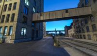 a long train track next to a tall building with windows and a bridge above it