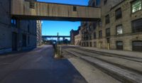 a long train track next to a tall building with windows and a bridge above it