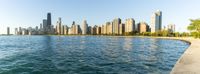 the city skylines of chicago as seen from lake michigan in summer with gentle water and large grassy area to foreground