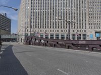 a metal bridge over a brick street with buildings behind it and an american flag at the end