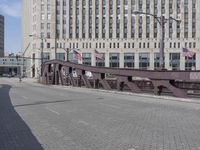 a metal bridge over a brick street with buildings behind it and an american flag at the end