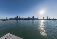 the city of chicago with skyscrapers and water in foreground on a clear, sunny day