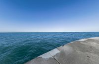 a concrete pier over looking the ocean on a clear day in late summer stock photo