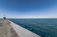 the blue sea is still visible near a concrete wall with a sign on it that says stop