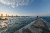 the city of mumbai from the end of a pier on a lake at sunset time