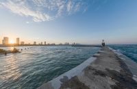 the city of mumbai from the end of a pier on a lake at sunset time