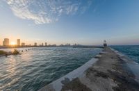 the city of mumbai from the end of a pier on a lake at sunset time