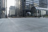 a city street with tall buildings and a metal globe sculpture in the middle of it