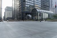 a city street with tall buildings and a metal globe sculpture in the middle of it