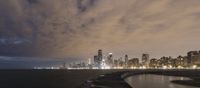 a city and a body of water under a cloudy sky near the shore line at night