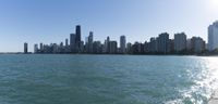 a body of water near a city with tall buildings in the background with sunlight shining from above and buildings along side of it