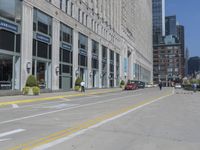 several people are walking through a deserted city street with tall buildings on either side of it